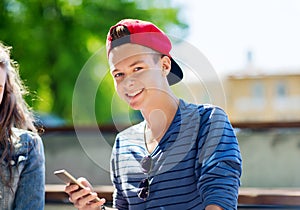 Happy teenage boy with smartphone outdoors