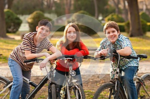 Happy teenage boys and girl having fun on bicycles