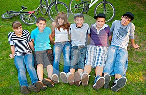 Happy teenage boys and girls resting in the grass