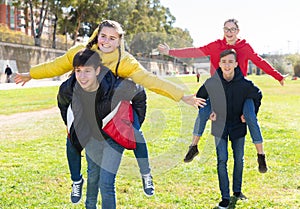 Happy teenage boys piggybacking girls