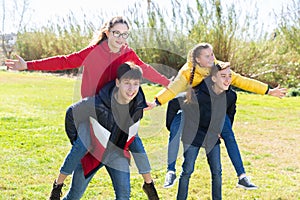 Happy teenage boys piggybacking girls