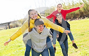 Happy teenage boys piggybacking girls