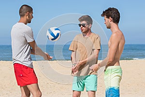 happy teenage boys playing beach volleyball