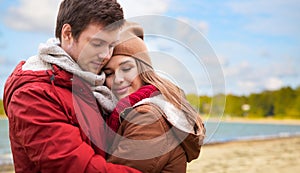 Happy teenage couple hugging over autumn beach