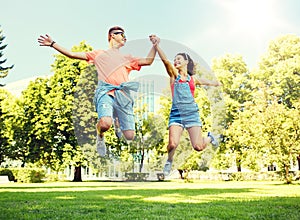 Happy teenage couple jumping at summer park