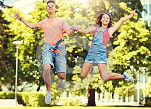 Happy teenage couple jumping at summer park