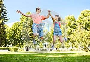 Happy teenage couple jumping at summer park