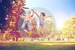 Happy teenage couple jumping at summer park