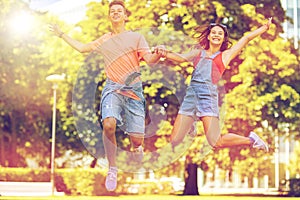 Happy teenage couple jumping at summer park