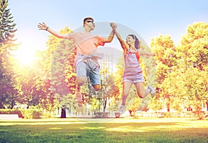 Happy teenage couple jumping at summer park