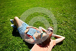 Happy teenage couple lying on grass at summer