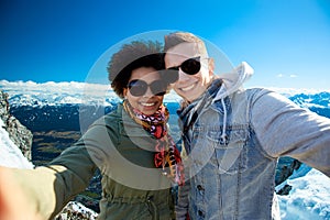 Happy teenage couple taking selfie over mountains