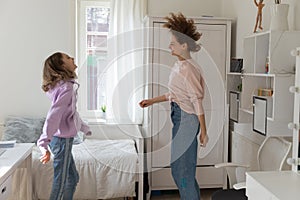 Happy teenage daughter and mother having fun, dancing at home