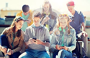 Happy teenage friends with smartphones outdoors