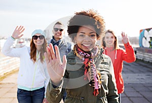 Happy teenage friends waving hands on city street photo