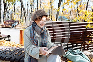 Happy teenage girl in autumn park on video call through laptop