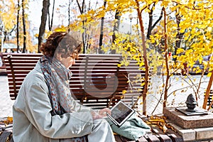 Happy teenage girl in autumn park on video call through laptop