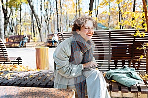 Happy teenage girl in autumn park on video call through laptop