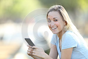 Happy teenage girl holding phone looking at camera