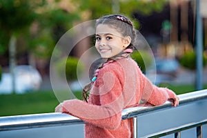 Happy teenage girl leaning against railing. Teenage girl smiling outdoors. Teenage and girlhood photo
