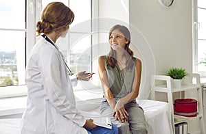 Happy teenage girl is listening to doctor during medical examination in modern clinic.