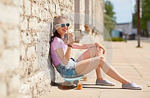 Happy teenage girl with longboard eating ice cream