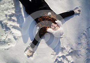 Happy teenage girl lying in the deep snow