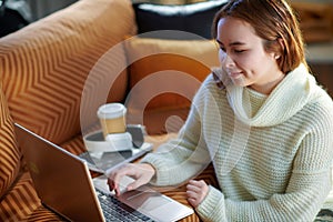 Happy teenage girl at modern home in sunny winter day reading