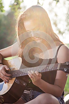 Happy teenage girl playing a guitar