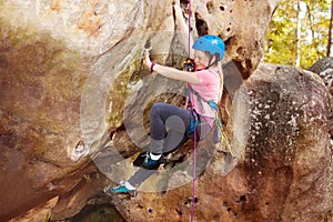 Happy teenage girl rock climbing in forest area