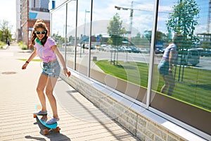 Happy teenage girl in shades riding on longboard