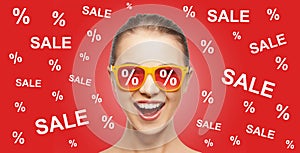 Happy teenage girl in shades with sale signs