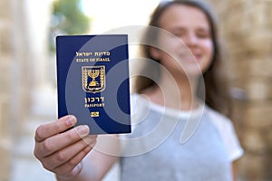 Happy teenage girl showing the passport of the State of Israel holding it in hand