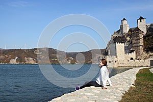 Happy teenage girl is sitting by the river Golubac fortress photo