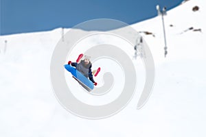 Happy teenage girl sliding down on snow tube