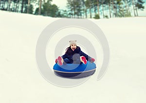 Happy teenage girl sliding down on snow tube