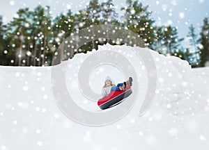 Happy teenage girl sliding down on snow tube