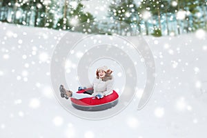 Happy teenage girl sliding down on snow tube