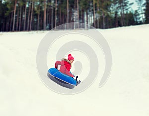Happy teenage girl sliding down on snow tube