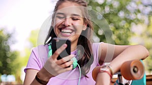 Happy teenage girl with smartphone and longboard