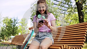 Happy teenage girl with smartphone and longboard