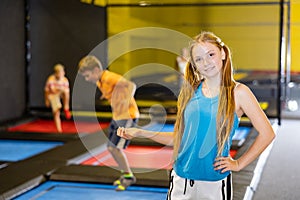 Happy teenage girl standing in indoor trampoline arena