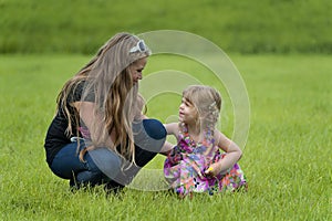 Happy teenage girl and a toddler in the grass