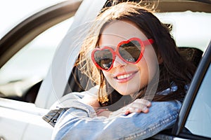 Happy teenage girl or young woman in car