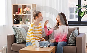 Happy teenage girls doing make up at home