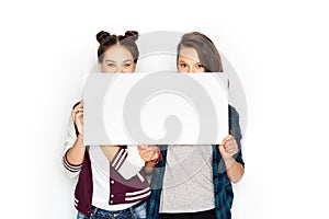 Happy teenage girls holding blank white board