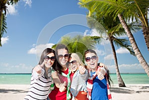 Happy teenage girls showing thumbs up on beach