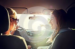 Happy teenage girls or women in car at seaside