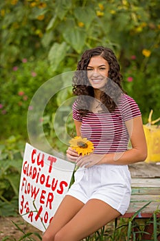 Happy teenage high school senior girl in sunflower field