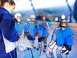 Happy teenage hockey players with coach on rink